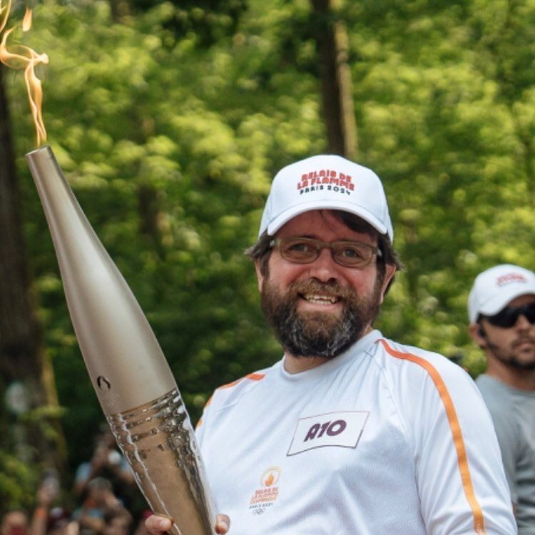 Nicolas, porteur de flamme pour les JO de Paris 2024 Nicolas Linder en maillot de sport, portant la flamme olympique des Jeux Olympiques 2024