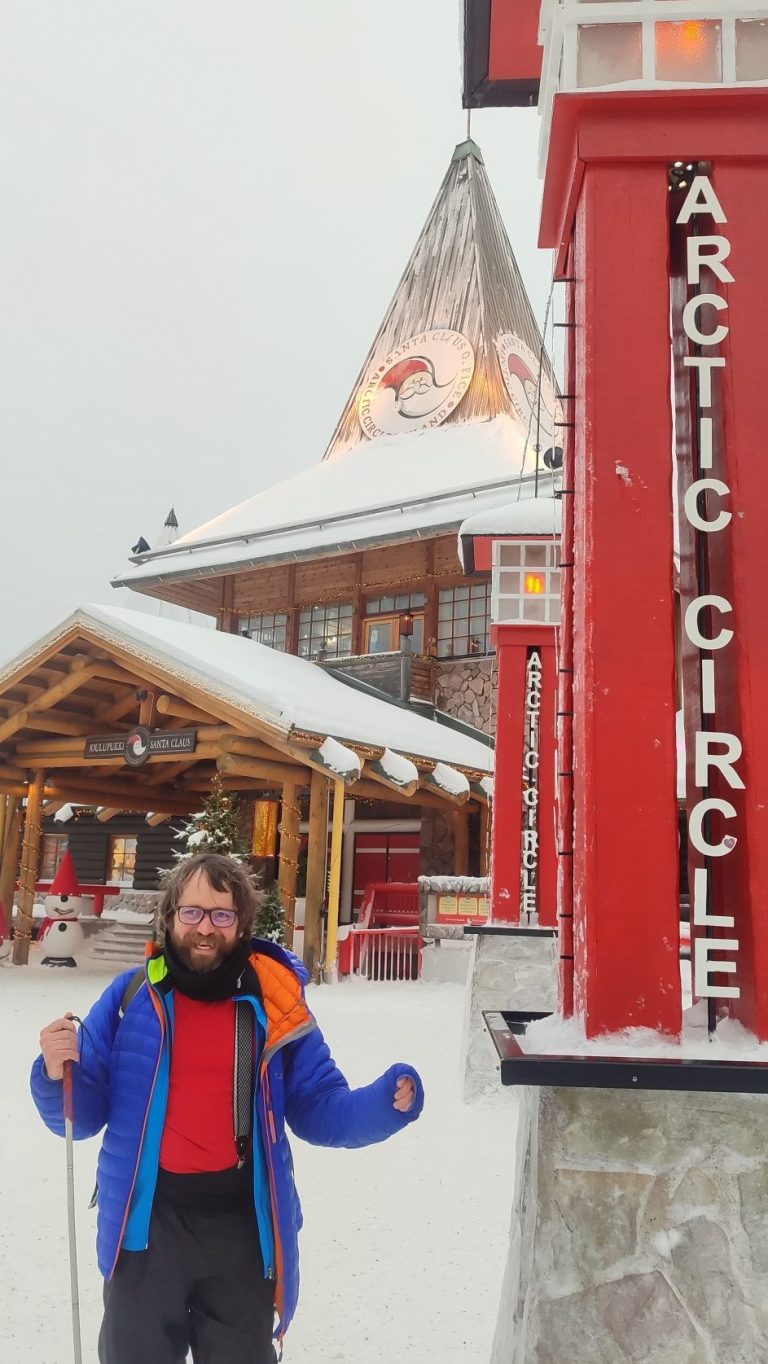 Audiodesk : Nicolas Linder, devant un poteau indiquant cercle polaire arctique